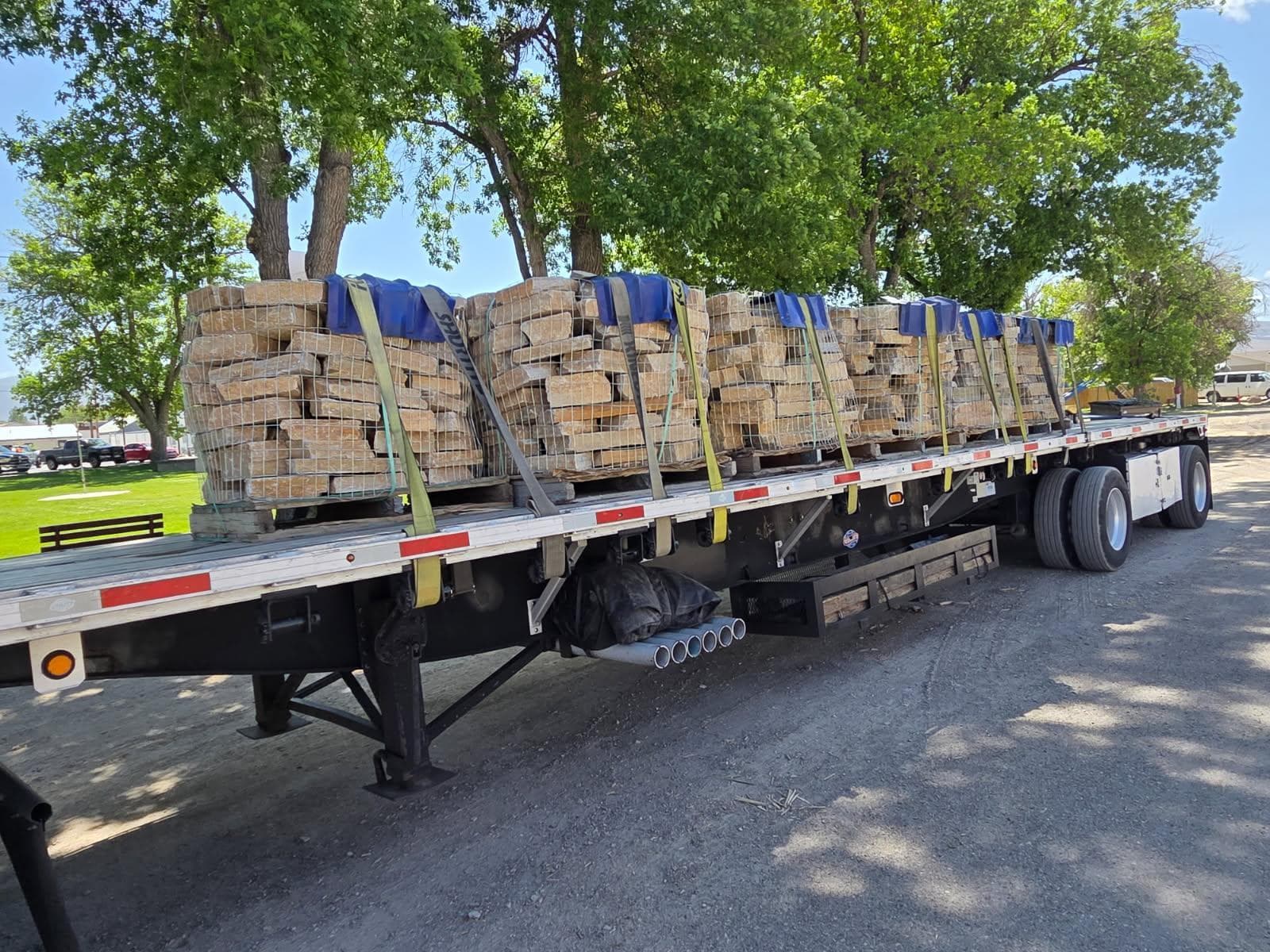 Palletized stone and building materials secured on a flatbed trailer.